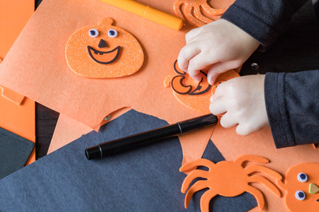 Small child doing autumn crafts at home, school or kindergarten. Halloween children party and diy concept.の写真素材
