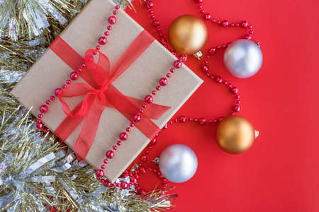 Christmas composition on red background with copy space. New year gift box with holiday decorations