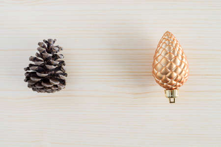 Pine cones on wooden background. Opposites concept. New versus old, natural versus artificial.