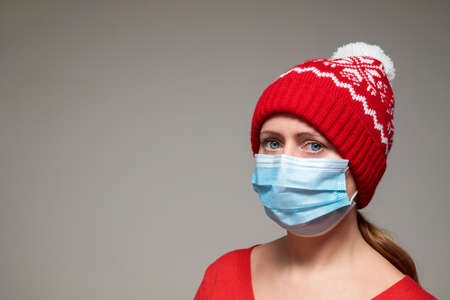 Young woman wearing face mask and Christmas red hat. Portrait of female adult. virus protection and prevention, wear mask, stay safe during pandemic concept. Copy spaceの写真素材