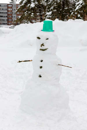 Snowman in yard near house on snowy cold winter day. Fun outdoor activity for kids and family.の写真素材