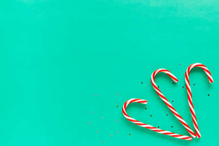Christmas white and red candy canes on green background with copy space for text. Minimalistic holiday flat layの写真素材
