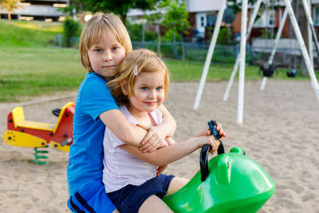 Children in park in summer. Brother hugging little sister. Siblings playing together at playground. Family activityの写真素材