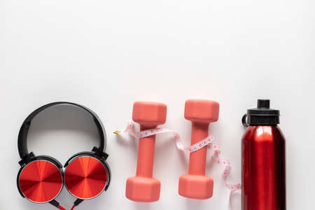 Fitness, sports and workout concept flat lay with copy space. Dumbbells, measuring tape, water bottle and headphones on white background.の写真素材