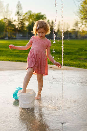 Little girl playing in park with fountains in summer Small child having fun at splash pad playgroundの写真素材