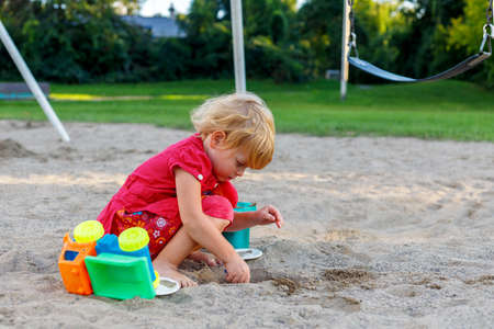 Little girl playing with sand and toys at playground in park. Small child outdoors in summerの写真素材