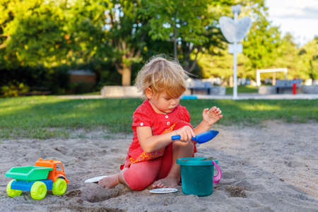 Little kid playing with sand and toys outdoors in summer. Child in park. Small girl at playgroundの写真素材