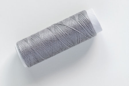 Grey sewing thread spool on white background, top view.