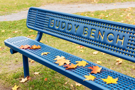 Blue buddy bench in the public park near school in fall