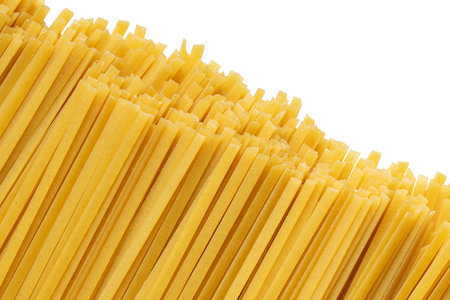 Pile of uncooked durum fettuccine pasta isolated on white background. Raw spaghetti or noodlesの写真素材
