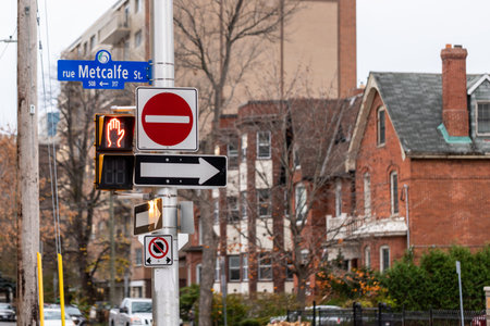 Ottawa, Canada - November 6, 2022: Red stop sign, arrow indicating the direction of traffic and traffic lights for pedestrians on the road with buildings in downtownのeditorial素材