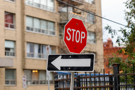 Red stop sign and arrow indicating the direction of traffic on the road