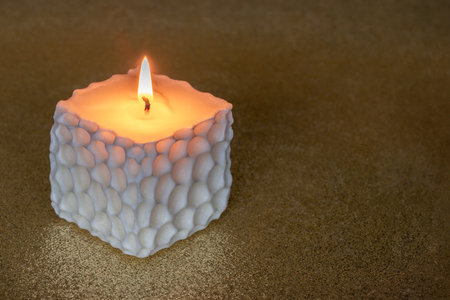 Cube handmade soy wax candle on golden background with copy apace.の写真素材