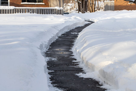 Winter road cleared of snow: Salt used to melt snow near houses.の写真素材