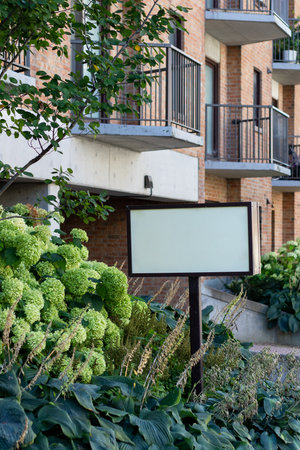 Blank advertisement sign for sale or rent near residential house. Apartment building or retirement home.の写真素材