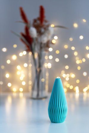Handmade candle on a table with dry flowers in a vase. Lights in background. Home decor. Cozy interior.の写真素材
