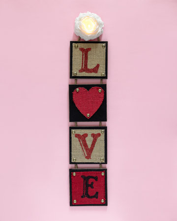 Pink background with red wall decor with word love and burning candle in flower shape. Valentine day and love concept.の写真素材