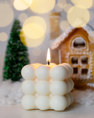 Christmas candle and decor with a decorative house and tree on a white table. Winter holiday decoration. Handmade soy wax candles.の写真素材