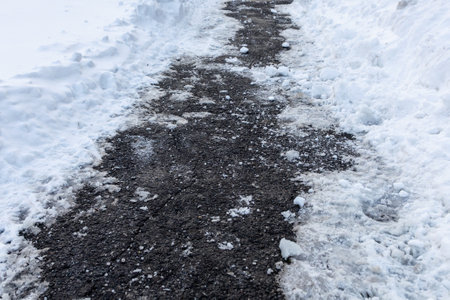 Sidewalk covered with salt and melting snow. Road for pedestrians in winter.の写真素材