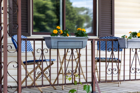 Porch of a house with table, chairs, and blooming flowers in pots in summer.の写真素材