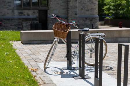 Retro bicycle with wicker basket parked at bike rack on sidewalkの写真素材