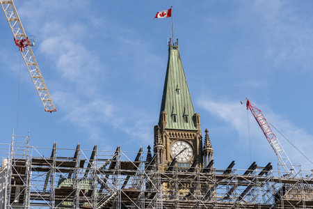 Parliament building Peace Tower with clock and Canadian flag under renovation in Ottawa, Canada. Scaffolding and cranes working in downtownの写真素材