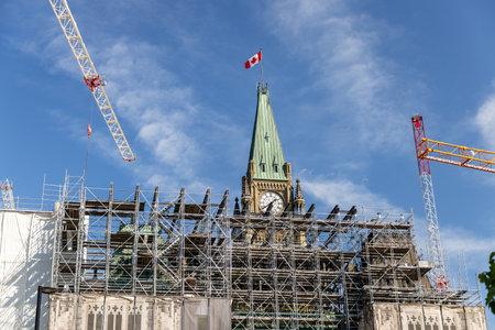 Parliament building Peace Tower with clock and Canadian flag under renovation in Ottawa, Canada. Scaffolding and cranes working in downtownの写真素材