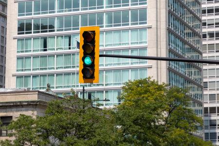 Green traffic light in city street. Urban signal against modern glass building in Montreal, Canada