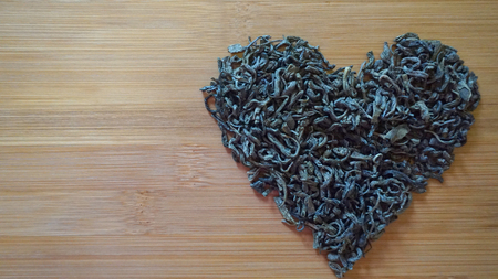 heart made of green tea on wooden bamboo textureの写真素材