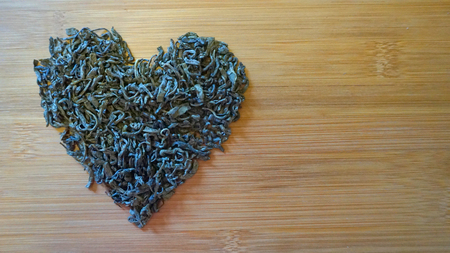 heart made of green tea on wooden bamboo textureの写真素材