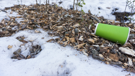 plastic take away coffee cup as trash on snow.の写真素材