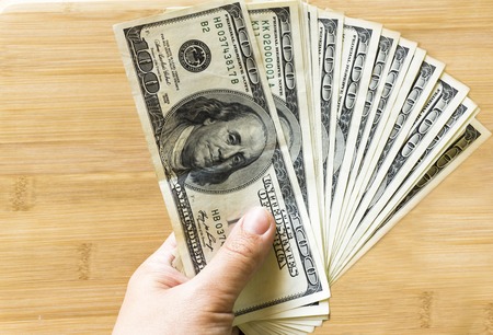 crolled stack of 100 new dollar bills on wooden backgroundの写真素材