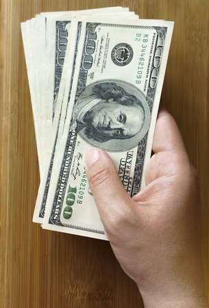 crolled stack of 100 new dollar bills on wooden backgroundの写真素材