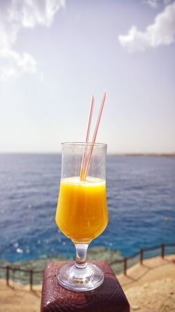 glass of fresh mango on the table on sea backgroundの写真素材