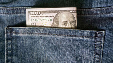 One hundred dollar banknote money in pocket jeans pants background texture. 100 dollar bill close up. Corruption.の写真素材