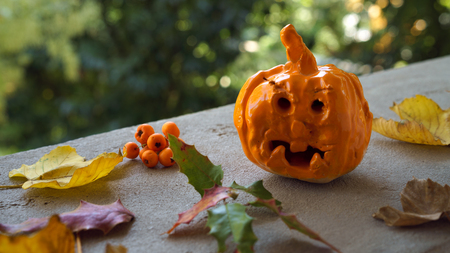 Autumn design with pumpkin ceramic handmade baby craft and fall leaves berries on orange and yellow colors. Happy Thanksgiving design.の写真素材