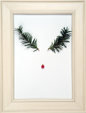 Creative layout of reindeer face made from two Christmas tree branches and red berry on frame. Nature New Year concept. Flat lay.の写真素材