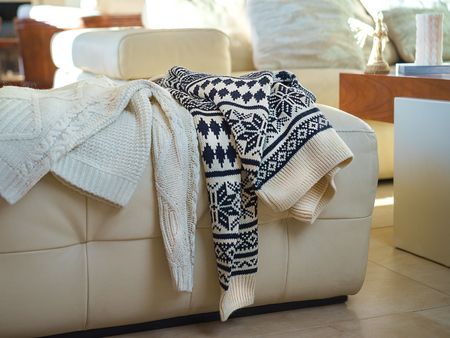 Warm winter sweaters for two people dropped on sofa after evening. Christmas Happy New Year Valentines Day concept. Close up romantic still life of sweaters of young couple in love. Black and white.の写真素材