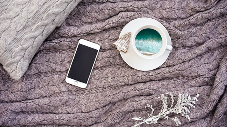 Top view white cup coffee with turquoise sea waves and waffle cookie in form fir and white phone...