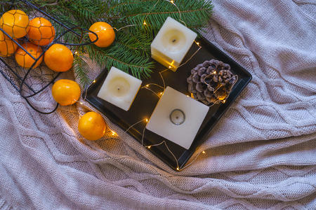 Flat lay Christmas decorations inspiration still life decor orange tangerines, pine cone candles on black tray cosy fairy lights on gray plaid background. winter card layout idea. top view copy spaceの写真素材