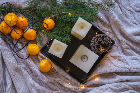 Flat lay Christmas decorations inspiration still life decor orange tangerines, pine cone candles on black tray cosy fairy lights on gray plaid background. winter card layout idea. top view copy spaceの写真素材