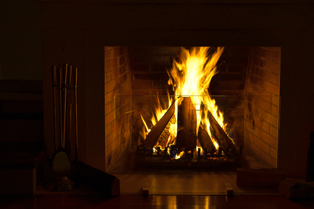 Wood burning in a cozy fireplace at home in interior. Fireplace as a piece of furniture. Christmas New Year concept decorations.の写真素材