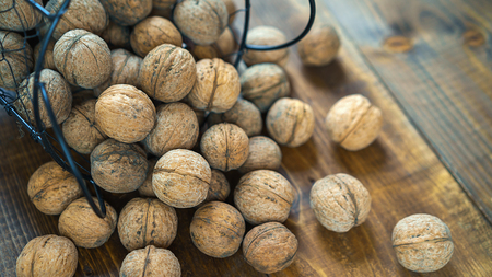 walnuts in the shell on old brown wooden table background in rustic style. Harvest nuts from country. Healthy ingredients for diet. Close up.の写真素材