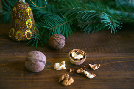 walnuts with shell, fir tree branch and Christmas decoration on rustic wooden background. you can...