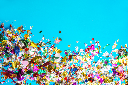 Bright colored confetti on blue paper background. Frame copy space. Top view, flat lay. Holiday party conceptの写真素材