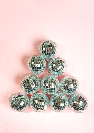disco balls for decoration party on pastel pink gradient background. Light silver disco balls making a shape of fir tree. Christmas New year concept. top view, flat lay. Frame with room for copy.の写真素材