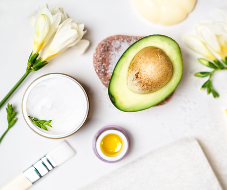 avocado and jar of cream oil lily flowers and sea salt soap white towel on a white background; Avocado skin care facial mask. Facial treatment concept. Flat lay, top view, copy space bloggingの写真素材