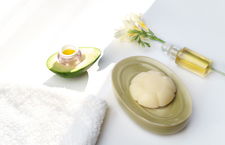 Beauty concept avocado, skin care facial essence oil, soap, lily flower and towel on white background. Facial treatment preparation for cosmetic clinic. beauty spa. copy space. Selective focus, trendの写真素材