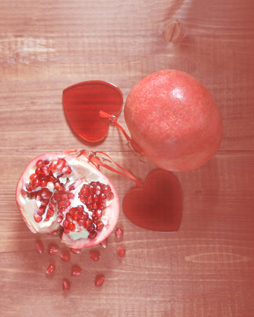 Panton color of the year 2019 - Living Coral. Abstract natural background fresh peeled pomegranates with ruby red beans in love with two hearts on old wooden table. toned Valentines day conceptの写真素材