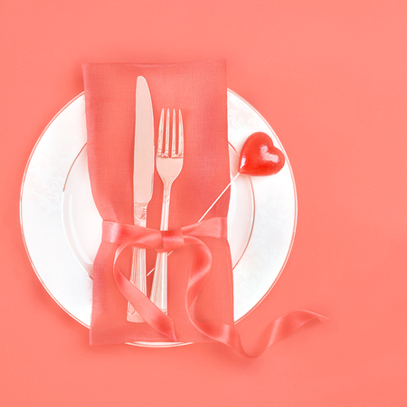 Panton color of the year 2019 - Living Coral. top view romantic table setting Valentines day dinner date celebration wedding with rose bud on plate on tablecloth coral pastel color background. tonedの写真素材